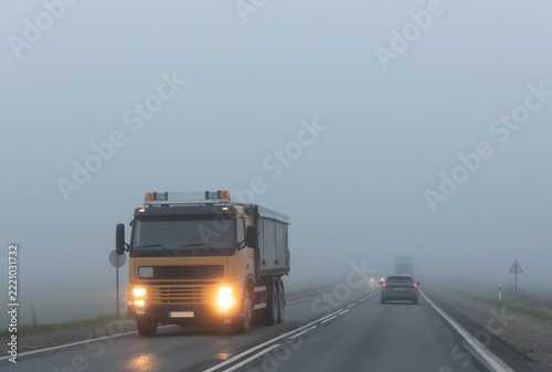 Truck on a country road in the thick fog. Poor visibility conditions on the road.