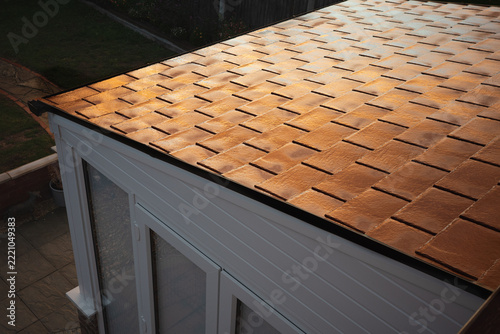 The light from a sunset illuminating the wet tiles of a conservatory roof.