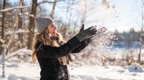 Smiling woman throwing snow in the air at sunny winter day