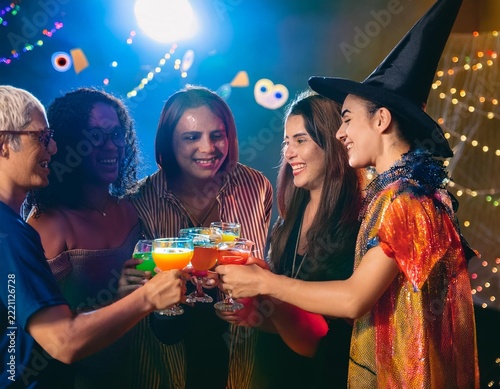 Friends Celebrating Halloween Party with Colorful Cocktails and Jack O Lantern Decorations
