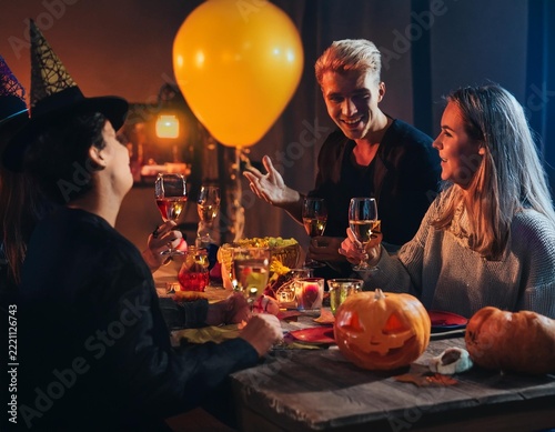 Friends Celebrating Halloween Party with Colorful Cocktails and Jack O Lantern Decorations