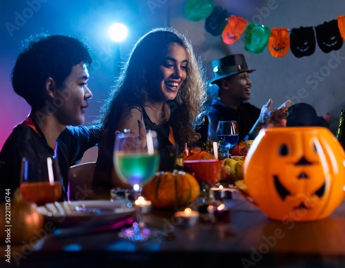 Friends Celebrating Halloween Party with Colorful Cocktails and Jack O Lantern Decorations