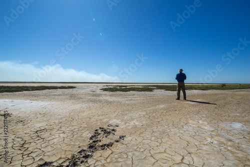 Tourist out on dry cracked mudflats at Derby