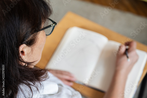 woman writing schedule in notebook for project, feedback and deadline in office. brainstorming ideas for development, journal and pen for planning. copy space, place for text