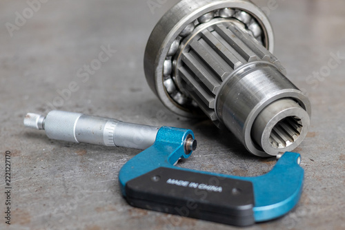 Precision micrometer lies near transmission spline shaft and ball bearing during maintenance inspection.