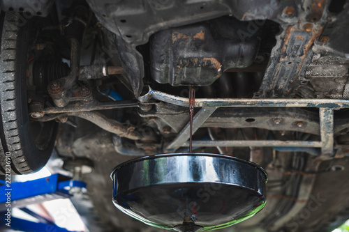 Auto mechanic draining dirty engine oil ,automotive engine oil change service.
