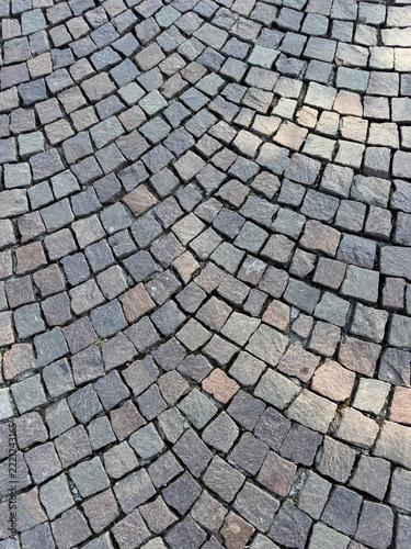 Gray porphyry cobblestone pavement laid in a fan pattern, background texture