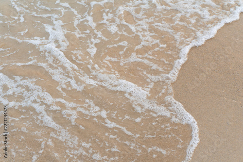 Sea water wave and foam washing and breaking on the beach shore background creating a peaceful vibe