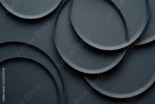 Stacked modern gray plates on dark textured surface
