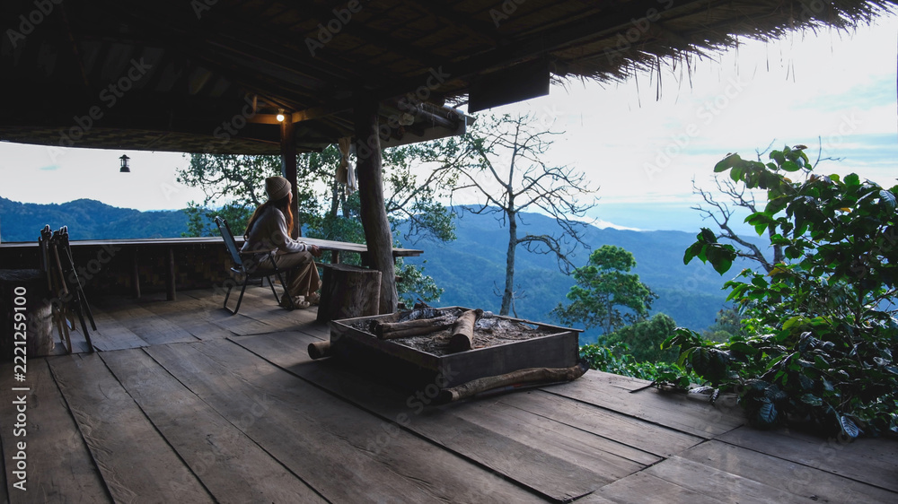 Fototapeta premium A woman sitting on wooden terrace and looking at nature views