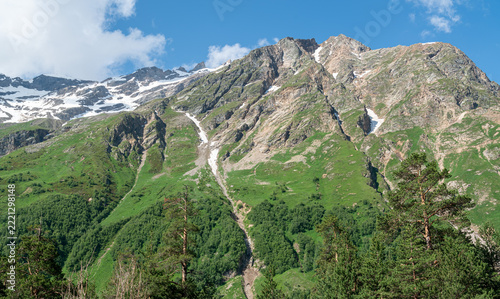 Mountains with green slopes and snow on peaks