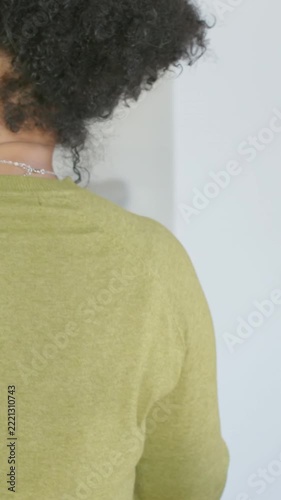 Vertical video: Shifting woman in green top turning at home near rail lowering arm holding phone