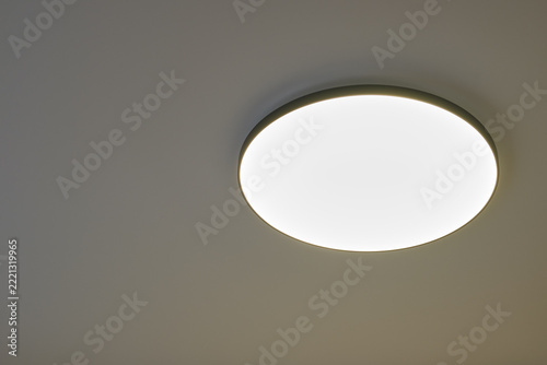 Led light fixture mounted on ceiling in indoor space provides illumination. Circular shape with even light distribution. Simple design fits well in modern home environment.