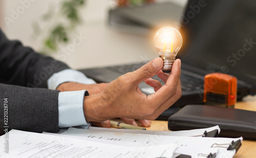 businessman holding lightbulb at workplace in office, idea thinking concept