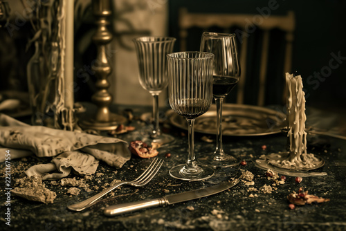 Fluted wine glasses and vintage tableware on a messy festive dinner table.