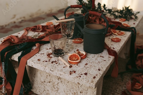 Table setting with watering cans, glassware, dried oranges and velvet ribbons.