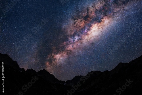 Starry night sky over dark mountain silhouettes with the Milky Way clearly visible in long exposure
