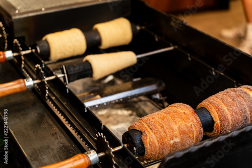 Traditional trdelnik pastry baking on rotating skewers over a hot grill in Prague city center