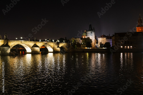 Illuminated Charles Bridge and historic architecture along the Vltava River in Prague at night