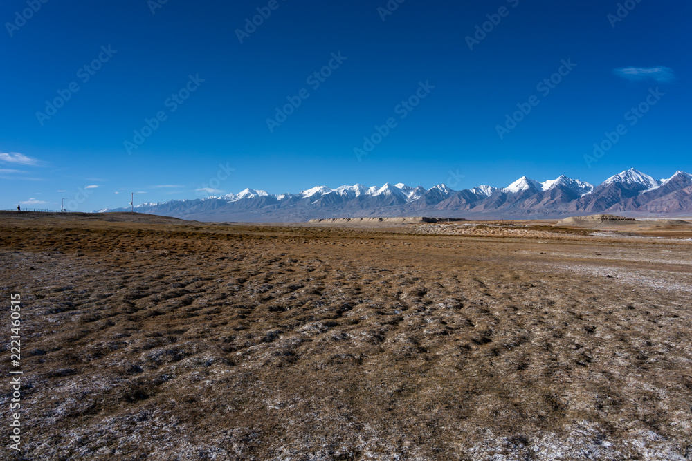 Fototapeta premium Pamir Plateau snow mountains and dry grassland landscape under blue sky