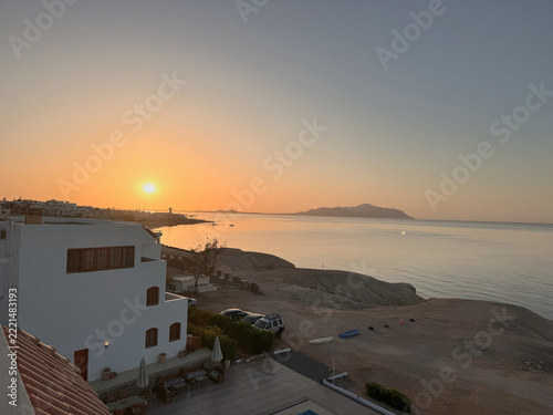 Fotografie Sunrise over the Red Sea seen from a hotel terrace in Sharm El Sheikh, Egypt, with the sun rising above a distant island