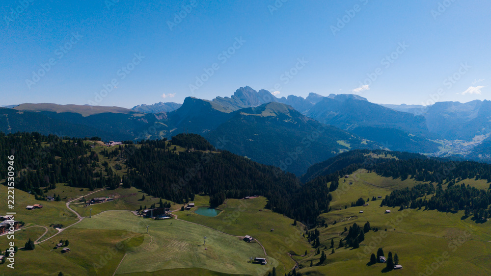 Fototapeta premium View of beautiful landscape in the Alps with fresh green meadows in the background on a sunny day with blue sky and clouds in summertime. Alpe de Siusi, Dolomite Alps