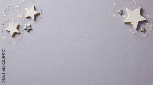 Minimalist Christmas background with wooden stars, fairy lights on gray concrete surface, holiday festive copy space