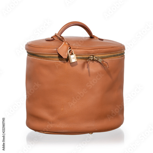 Brown leather cylindrical beauty case with gold hardware, lock, and clasp. Photographed against a white background.