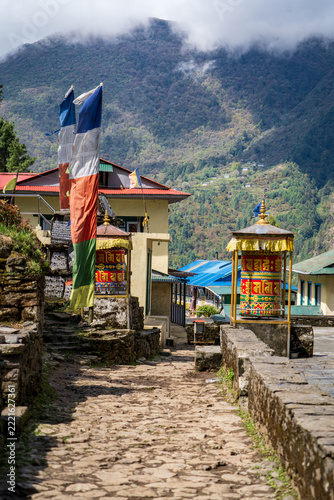 Fotografie Inscripciones, banderas y rueda de plegarias budistas en la región de los himalayas, en Nepal