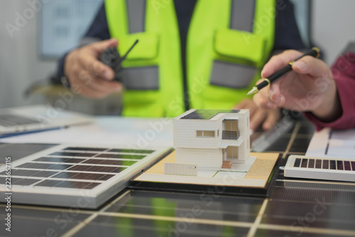 House model, solar panel, worker planning solar house with small model and solar panel in foreground
