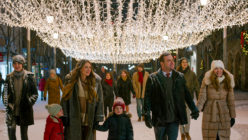 Pedestrians walk beneath a bright canopy of holiday