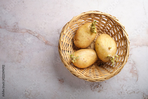 Raw Potatoes With Sprouts in a Woven Basket on a Light Surface