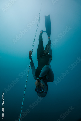 freediver descending headfirst beside a depth line