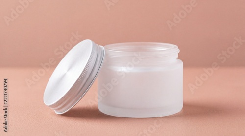 Open Frosted White Cosmetic Cream Jar with Detached Screw Lid on Soft Peach Pink Background.
