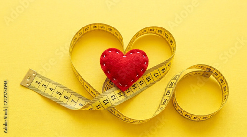 Healthy Lifestyle Heart Shape Measuring Tape on Yellow Background Weight Loss and Fitness Concept