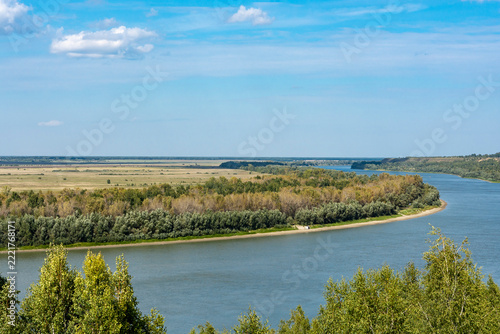The Siberian river, wide and peaceful, draws bizarre loops between green banks