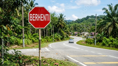 Stop Sign BERHENTI on a Winding Tropical Road with a Car