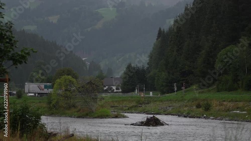Scenic mountain river flowing through rural alpine valley on rainy day