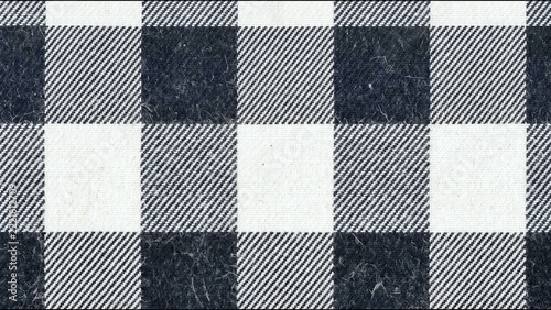 Black and white plaid fabric texture featuring repeating checkered geometric patterns with woven wool material