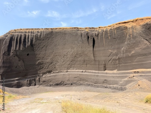Obraz na plátně Broad volcanic tuff cliff displays dark vertical erosion channels, horizontal st