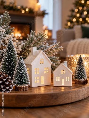 Miniature white ceramic houses and evergreen trees in a cozy winter interior