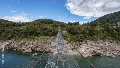 Young man on suspension bridge over Buller River, Buller Gorge Swing Bridge, Inangahua, West Coast, South Island, New Zealand
