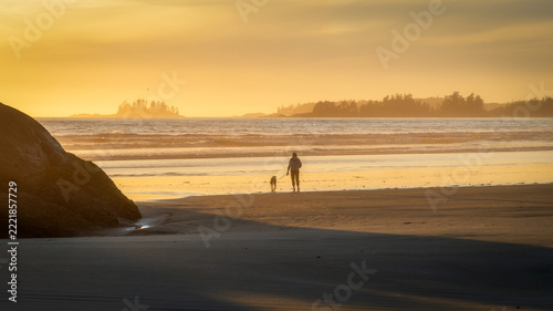 walking the dog on beach at sunset