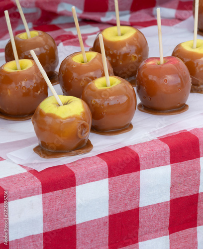 Caramel apples with sticks on red and white checked tablecloth