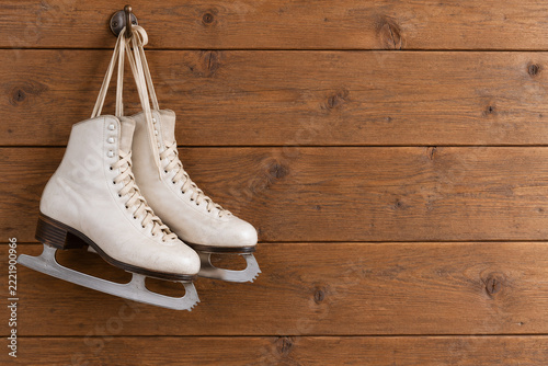 Vintage White Ice Skates Hanging on Rustic Wooden Wall
