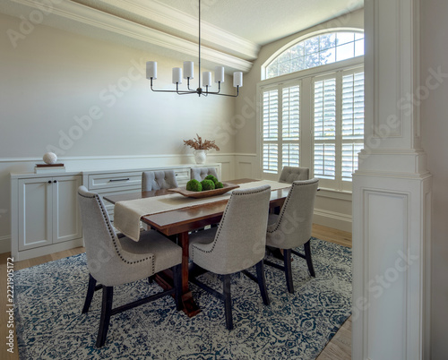 An upscale, modern formal dining room featuring a dark wood table paired with fabric upholstered chairs with nailhead trim.