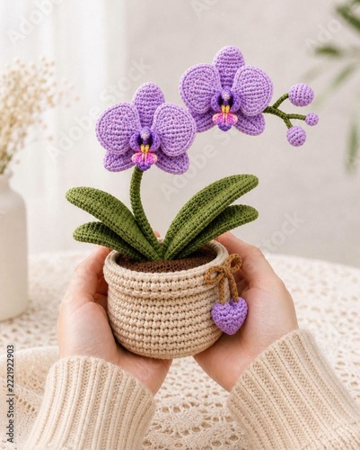 Handcrafted purple crochet orchid plant in beige woven pot held by female hands soft view.