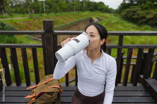 Obraz na plátně Asian sportswoman drinking water from bottle during break outdoors