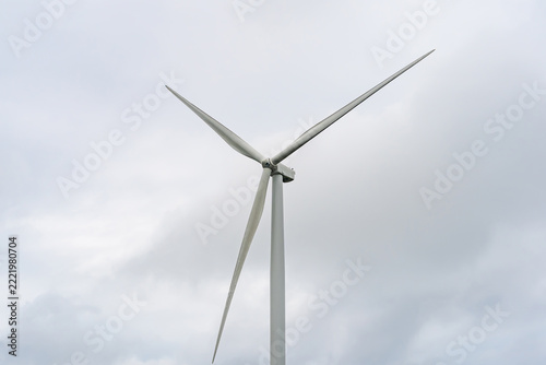 Wind Turbine Against Cloudy Sky: A modern wind turbine stands tall against a backdrop of dramatic, overcast skies, its blades poised to harness the power of the wind.