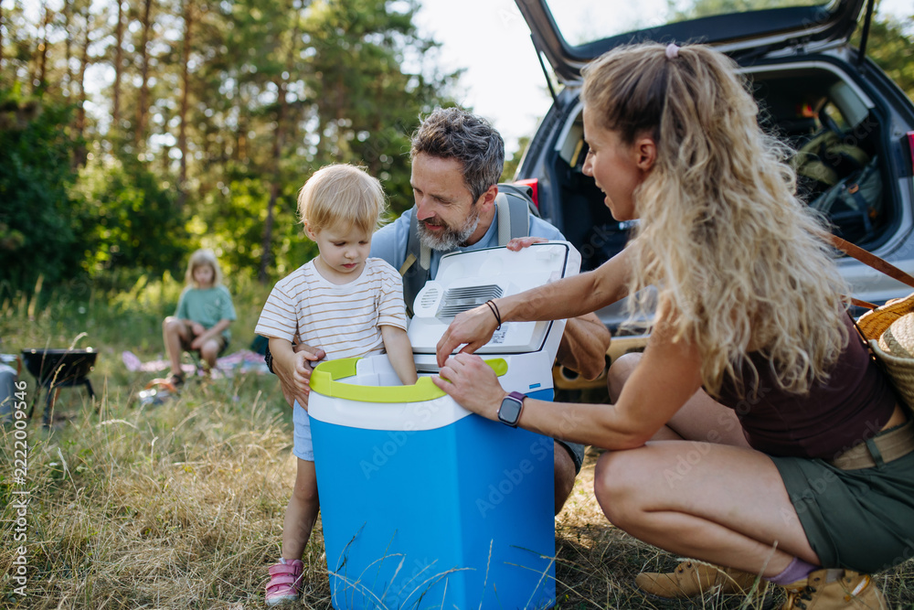 Naklejka premium Family unloading luggage from car and setting up a campsite.